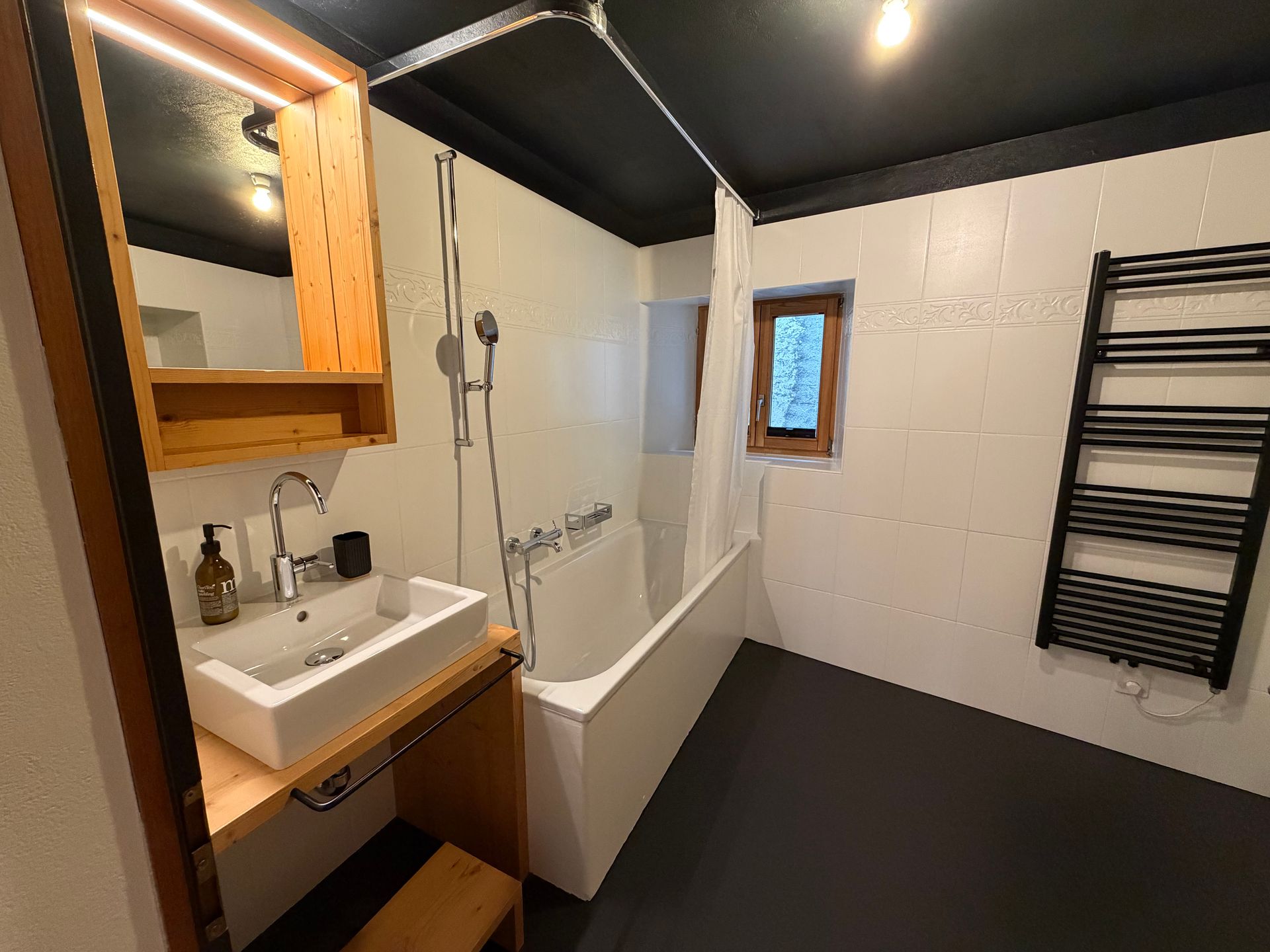 Grosszügiges Wohnzimmer mit Holzboden, braunen Stühlen und einem dunklen Barschrank an der Wand.