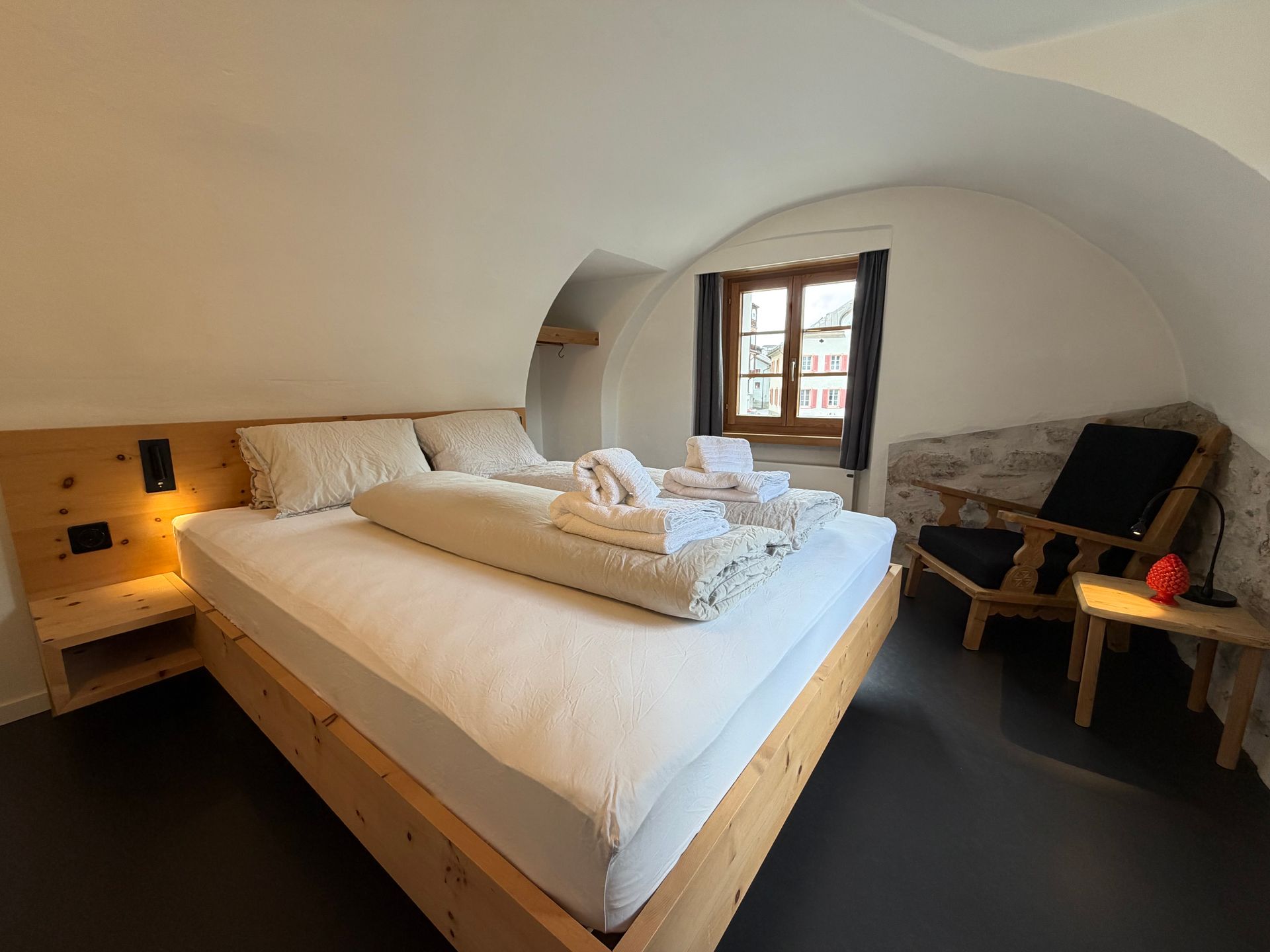 Gemütliches Schlafzimmer mit zwei Einzelbetten, Sofa, Esstisch und zwei Fenstern in holzgetäfelten Wänden