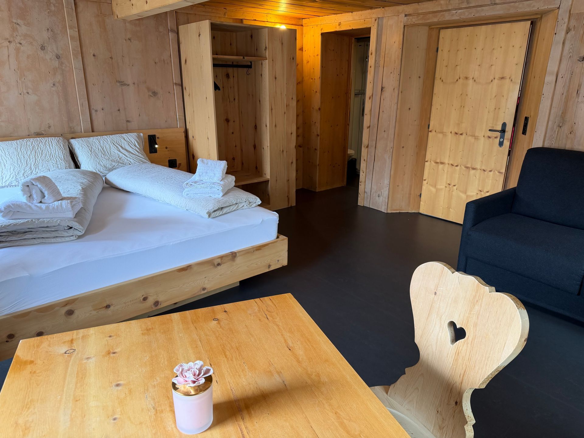 Kompaktes Badezimmer mit weissen Fliesen, Glasdusche, Wandwaschbecken, Spiegelschrank aus Holz und Fenster.