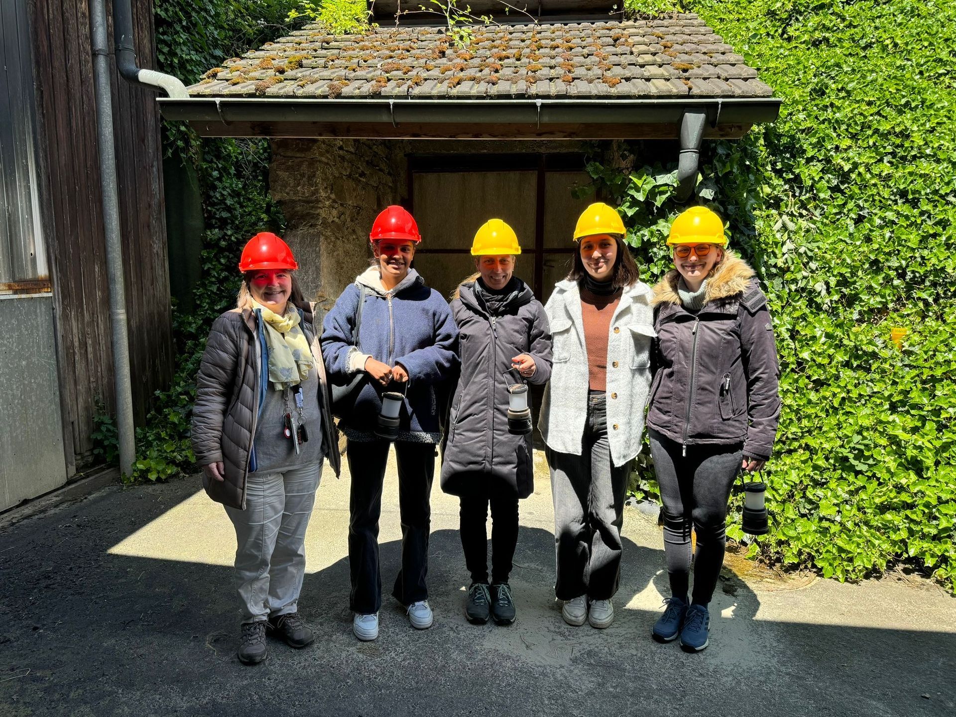 Eine Gruppe von Frauen mit Schutzhelmen steht vor einem Gebäude.