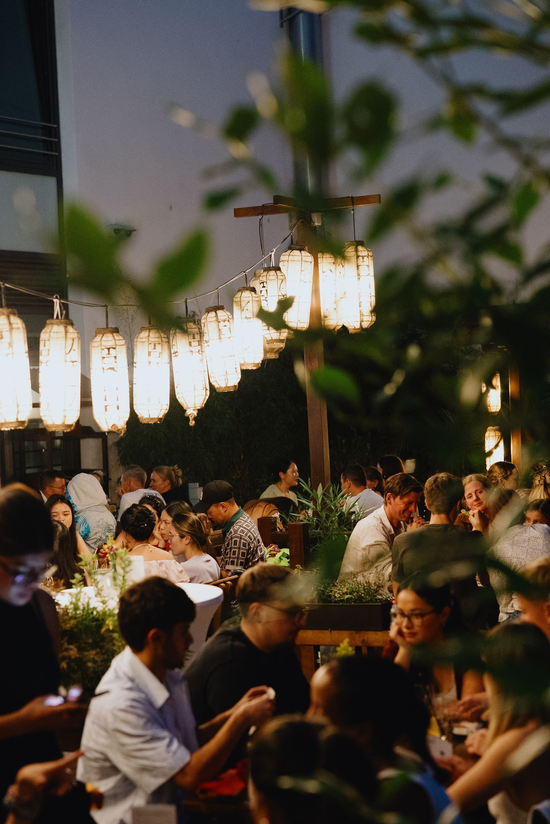 Teestube im japanischen Stil mit niedrigen Tischen, Kissen, Papierlaternen und strukturierten dunkelgrauen Wänden.