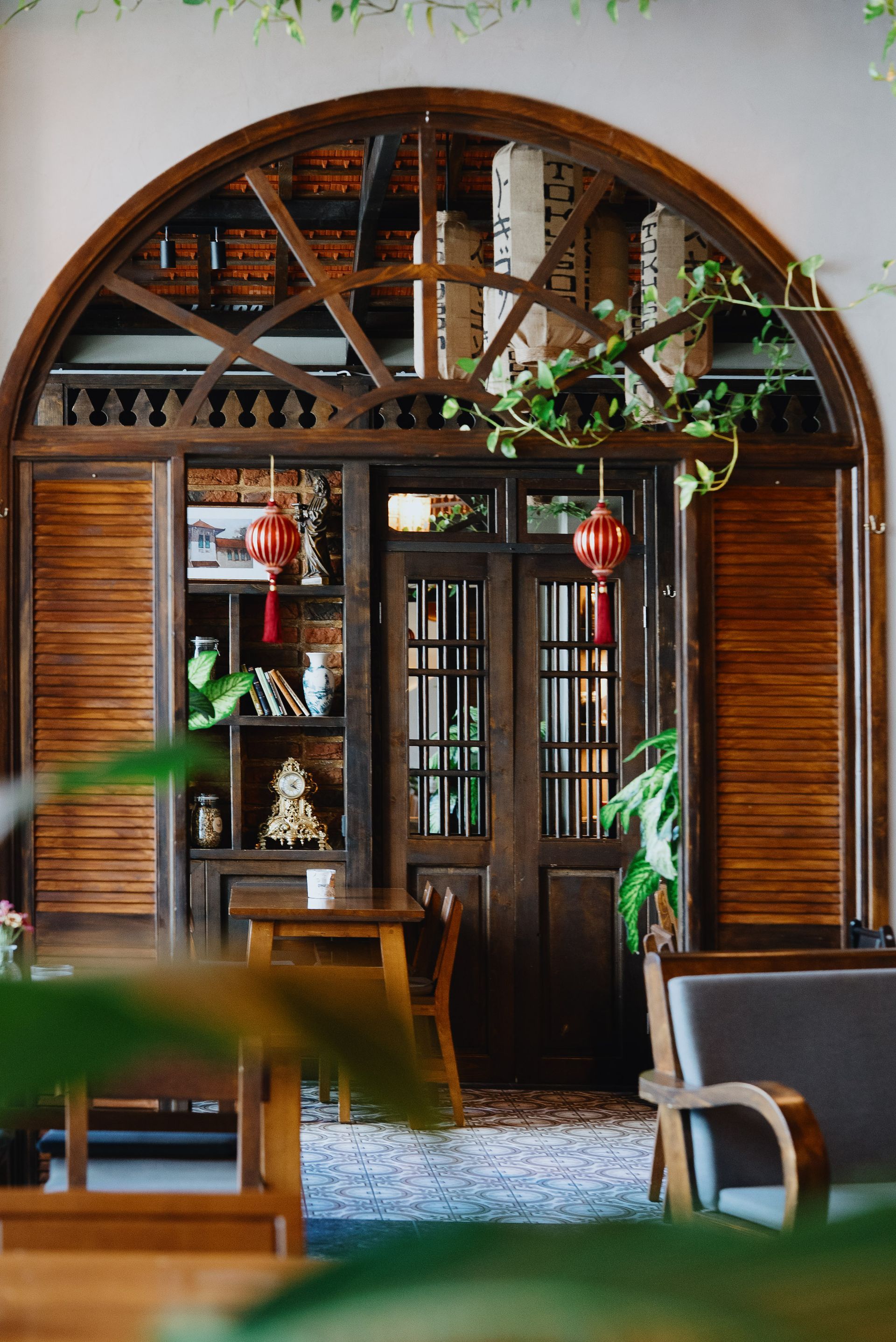Gemütliches Restaurantinterieur mit Holztischen und -stühlen, Laternenlichtern und einem dekorativen Fenster.