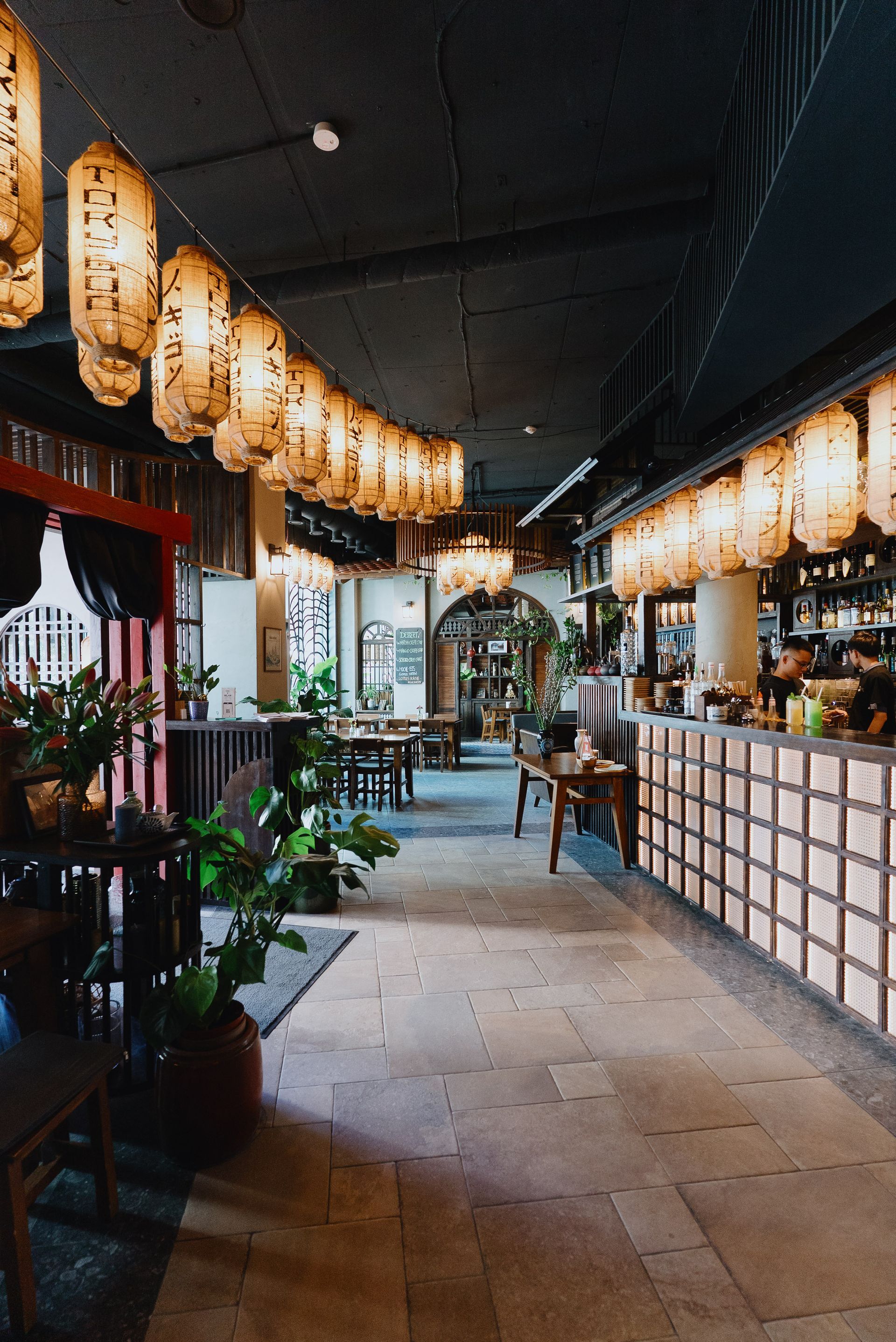 Gemütliches Interieur eines Cafés mit Holzwänden, Laternen und Tischen.