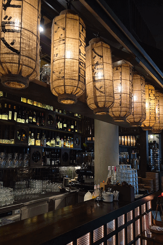Interieur eines japanischen Restaurants mit Papierlaternen, Bar und Schnapsflaschen.