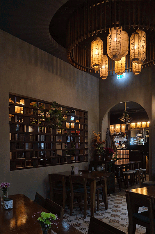 Gemütliches Restaurantinterieur mit Papierlaternen, Holztischen und dekorativer Wand.