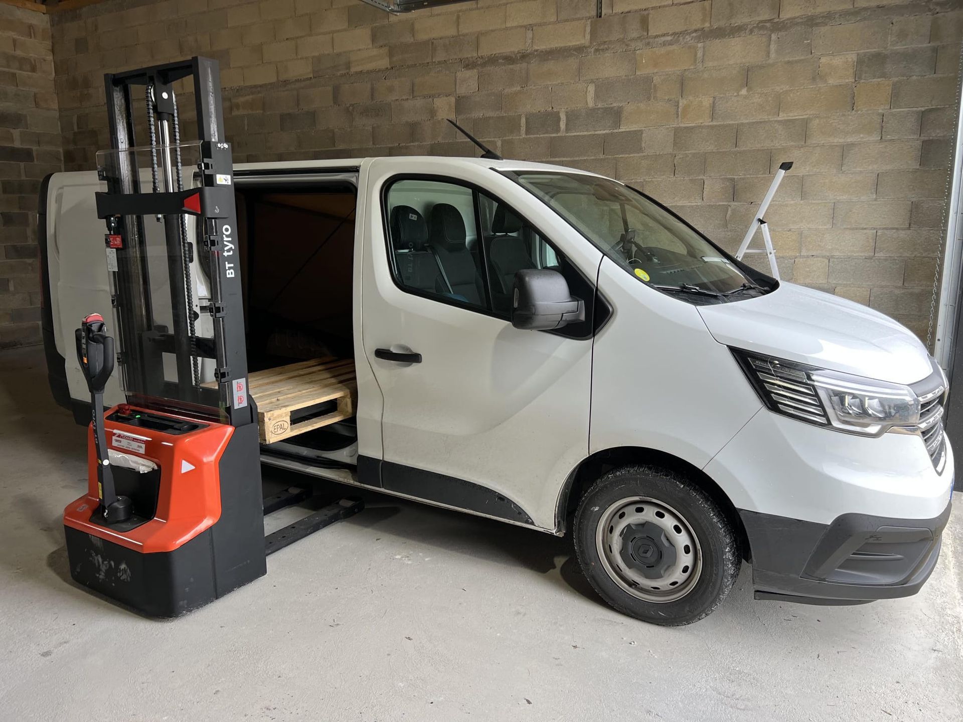 Véhicule de la société avec transpalette et palette vide.