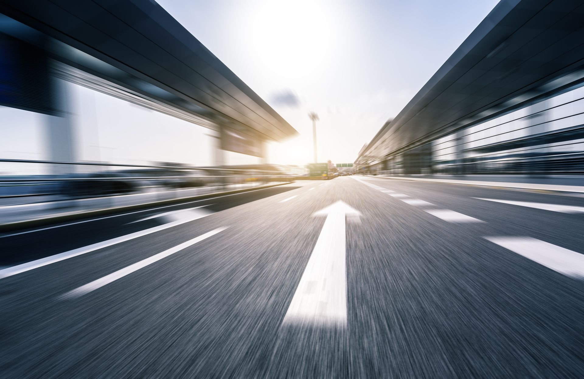 Vue à grande vitesse et floue d'une autoroute avec une grande flèche blanche peinte sur l'asphalte pointant vers l'avant.