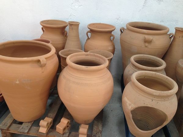 Un montón de ollas de barro están sobre una paleta de madera.