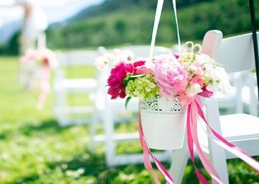 Un cubo de flores cuelga de una silla en una boda.
