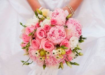 Una novia sostiene un ramo de flores rosas y blancas.