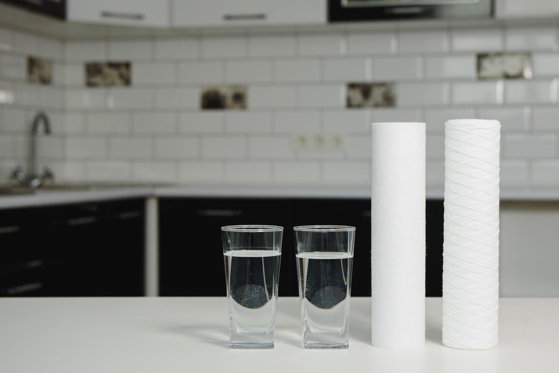 Accesorio de ducha cromado sobre pared de azulejos blancos con cabezal de ducha de mano.