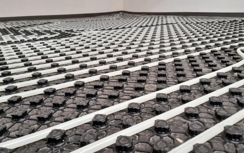 Accesorio de ducha cromado sobre pared de azulejos blancos con cabezal de ducha de mano.