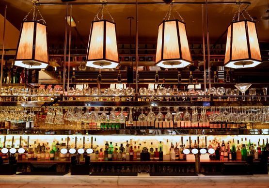 Un bar con muchas botellas y vasos colgando del techo.