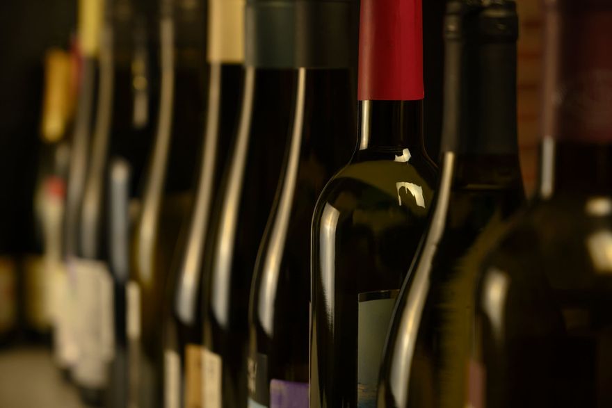 Una fila de botellas de vino están alineadas en un estante.