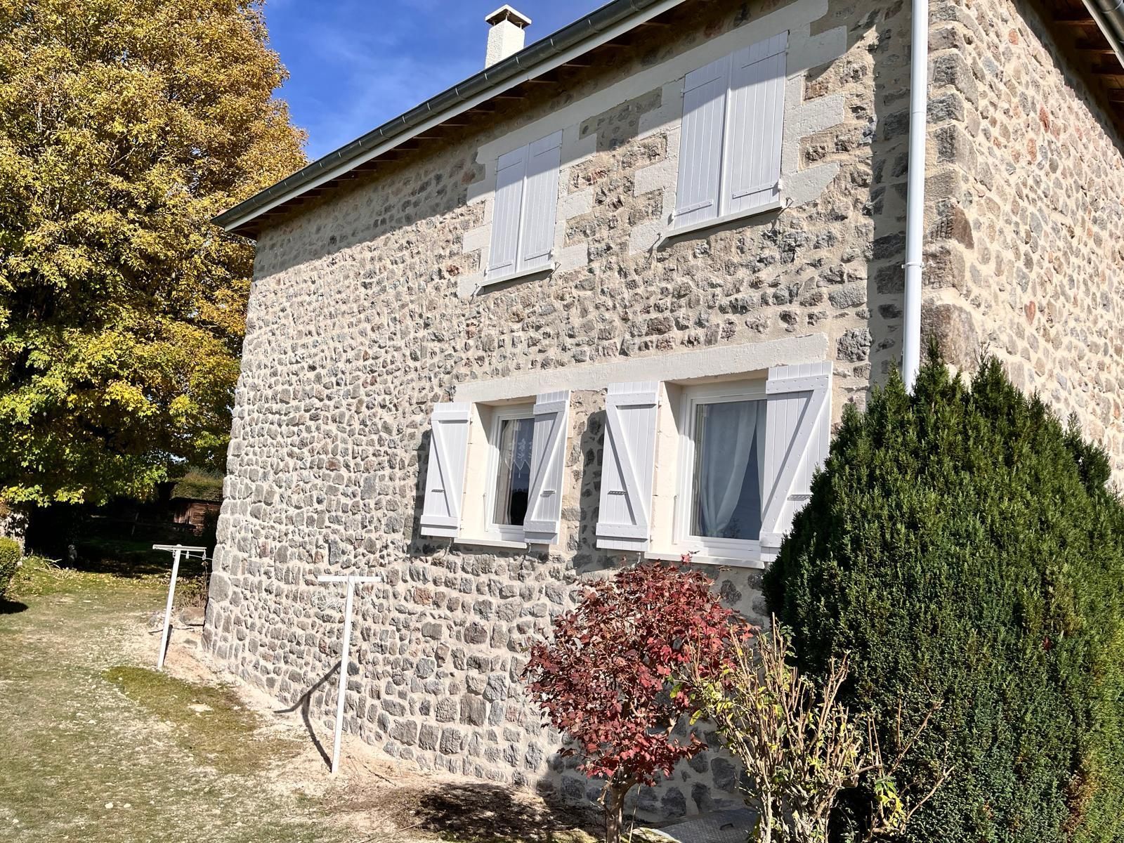 Façade de maison en pierres, quatre fenêtres sont apparentes