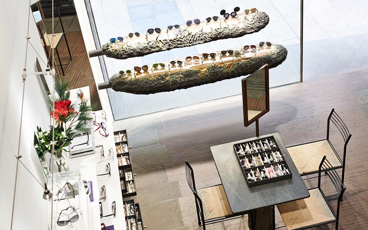 Vue aérienne d'un présentoir de magasin de lunettes avec deux structures flottantes. Une table et des chaises se trouvent au premier plan.
