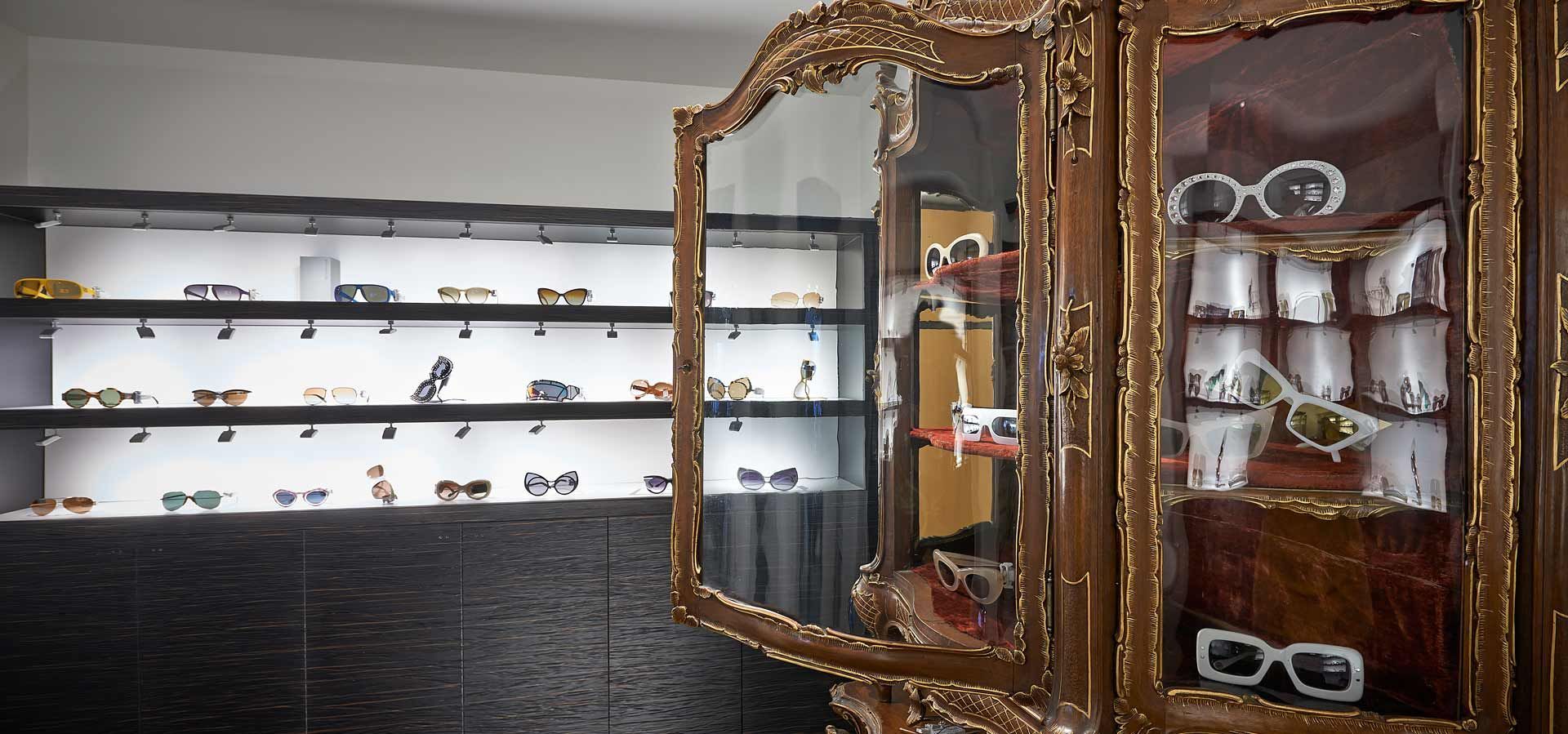 Lunettes de soleil exposées sur des étagères éclairées et une armoire décorative.