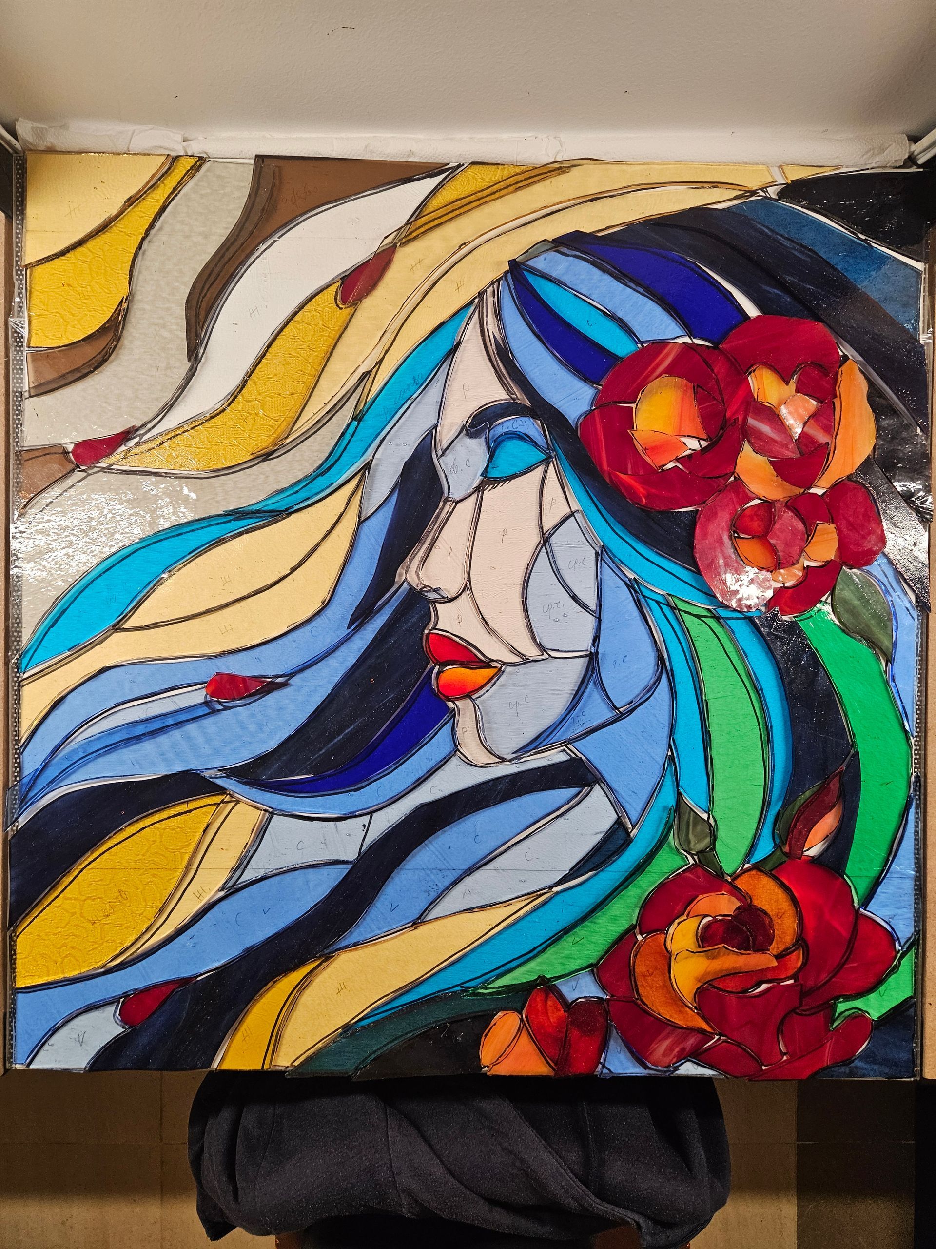 Una mujer está de pie junto a una pintura de vitral del rostro de una mujer.