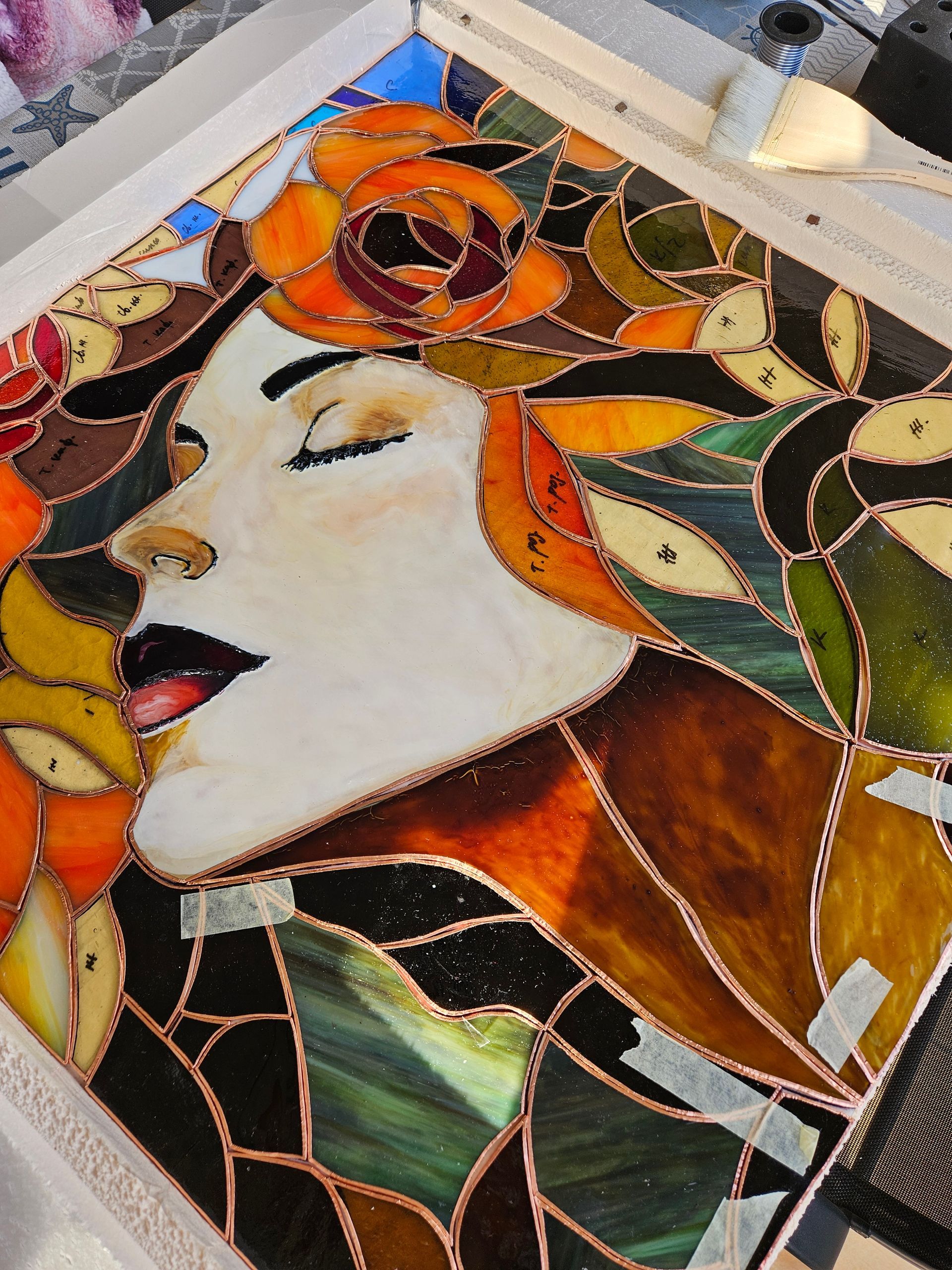 Una mujer está de pie junto a una pintura de vitral del rostro de una mujer.