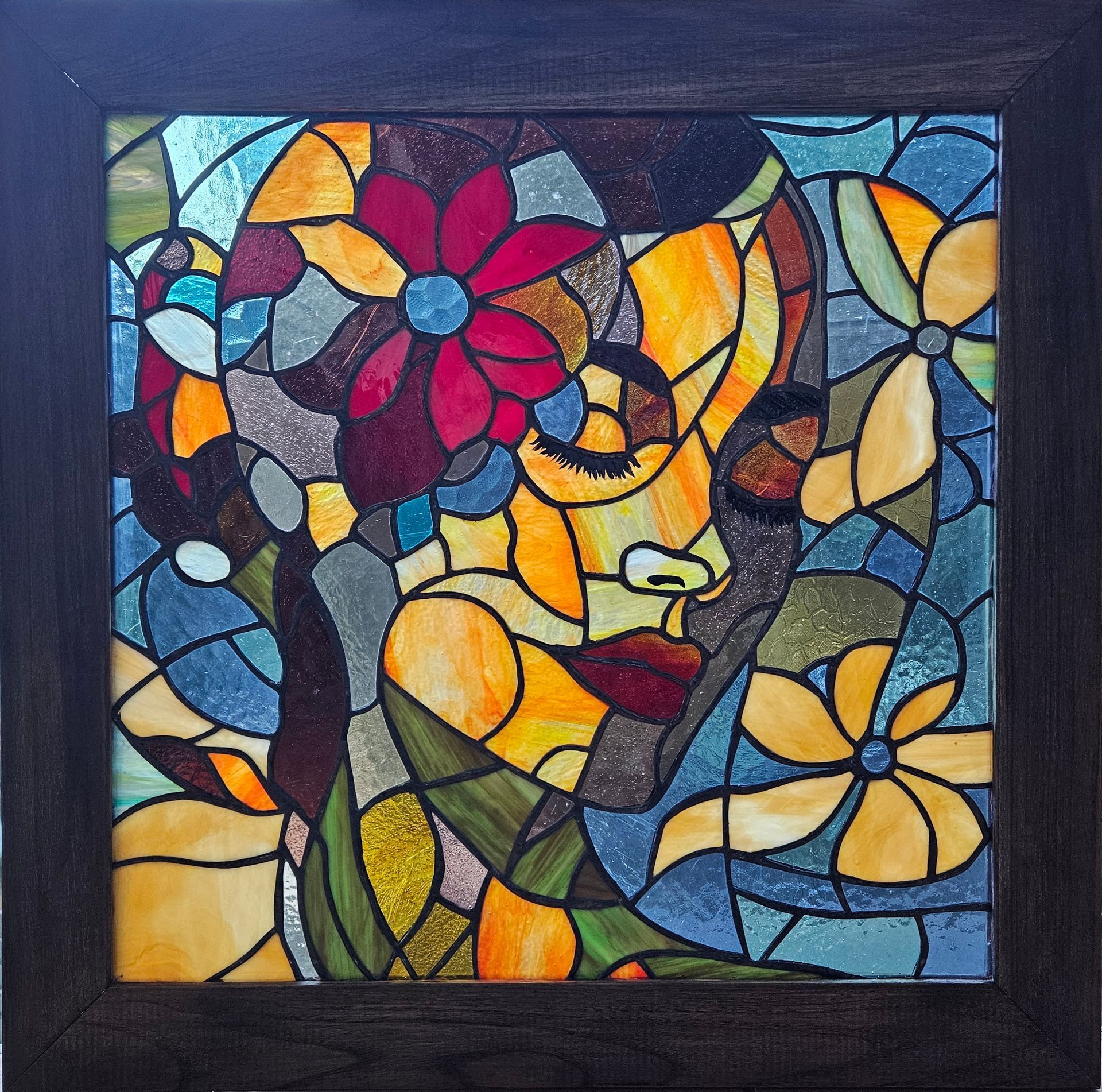 Una mujer está de pie junto a una pintura de vitral del rostro de una mujer.