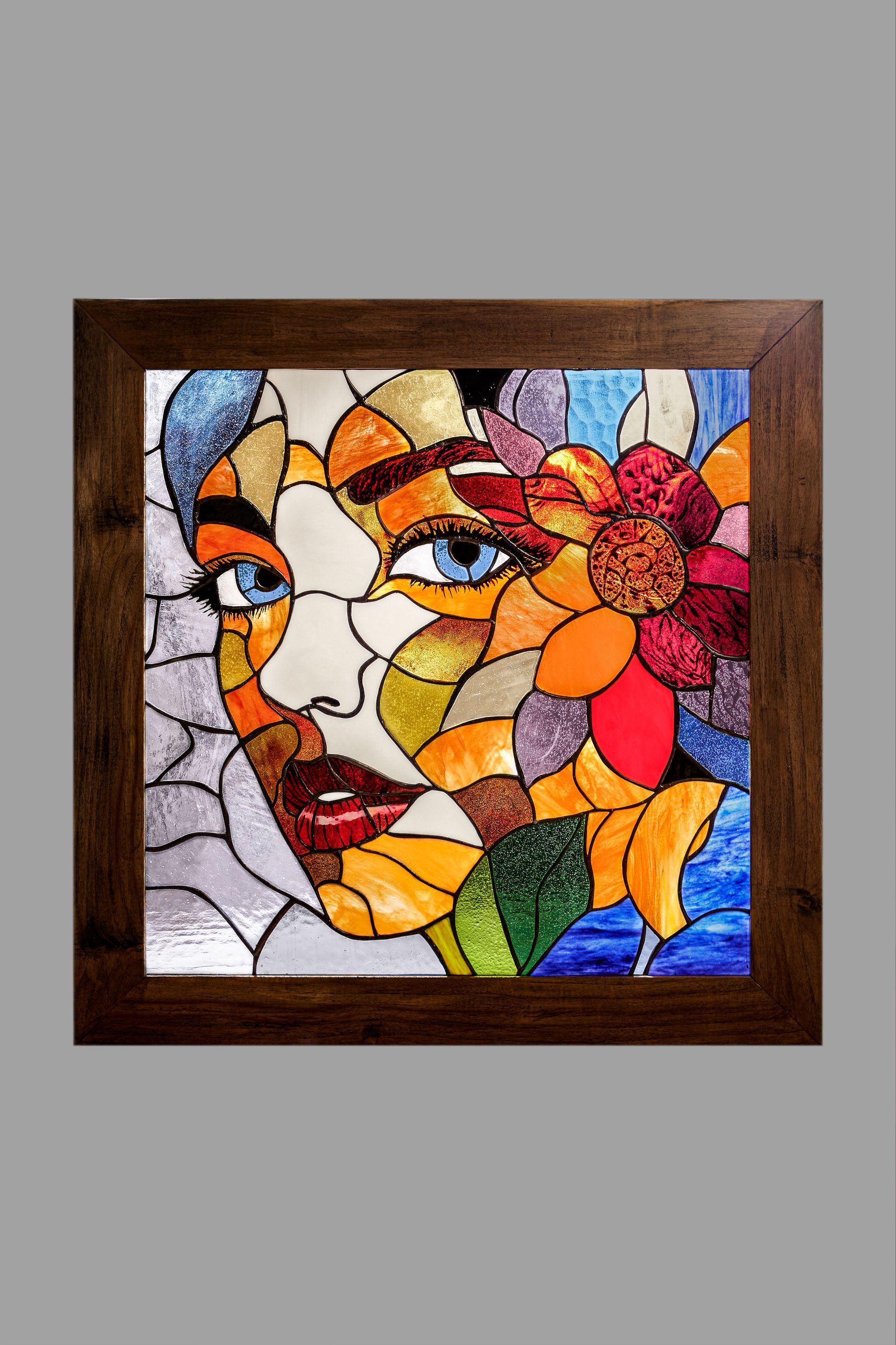 Una pintura de vidriera del rostro de una mujer con flores en un marco de madera.