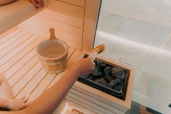 Una persona se está bañando en una sauna con un cubo de madera.