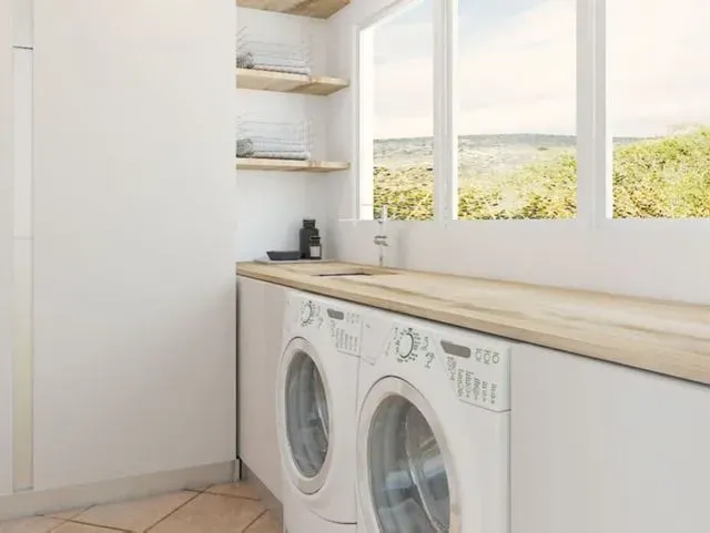 Un lavadero con lavadora y secadora y una ventana.