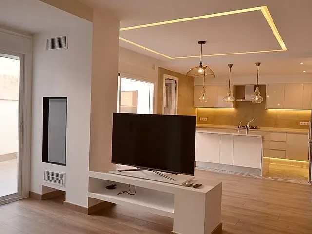 Una sala de estar con un televisor de pantalla plana sobre un soporte.