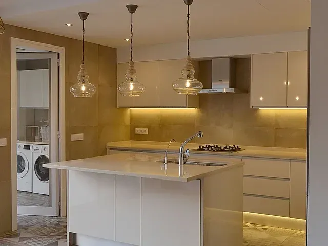 Una cocina con gabinetes blancos y una gran isla en el medio.