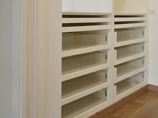 Un armario con muchos estantes y cajones y un piso de madera.