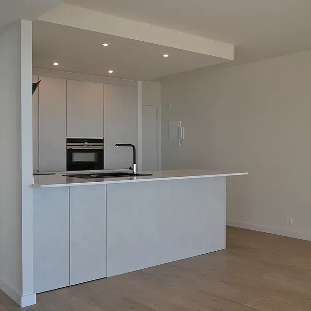 Una cocina con gabinetes blancos y una gran isla en el medio.