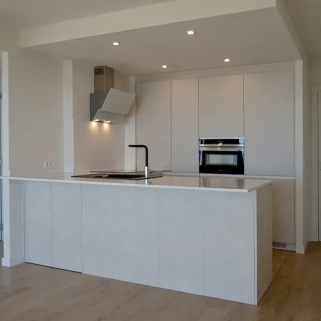 Una cocina con gabinetes blancos y una gran isla.