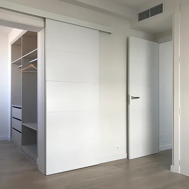 Un dormitorio con armario y puerta corredera.