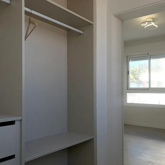 Un vestidor con un estante y una ventana en un dormitorio.