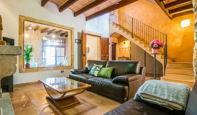 Una sala de estar con sofá, mesa de café, espejo y escaleras.