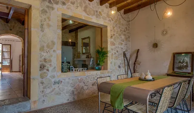 Un comedor con mesa y sillas y una pared de piedra.