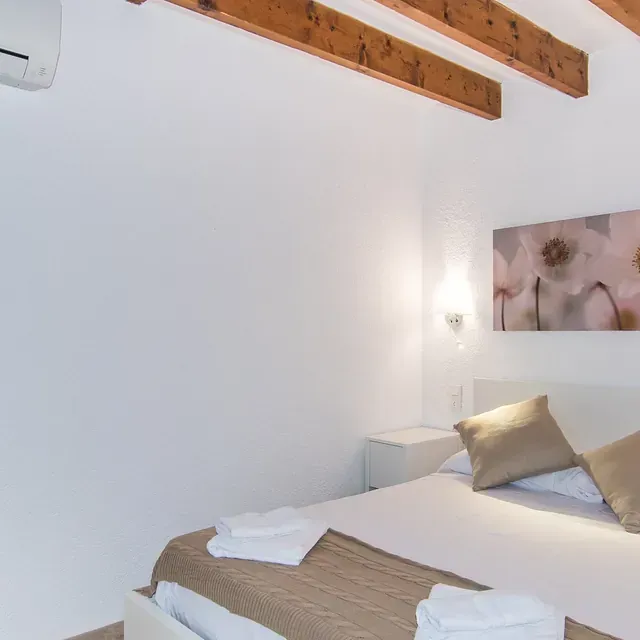 Un dormitorio con dos camas y un cuadro de flores en la pared.