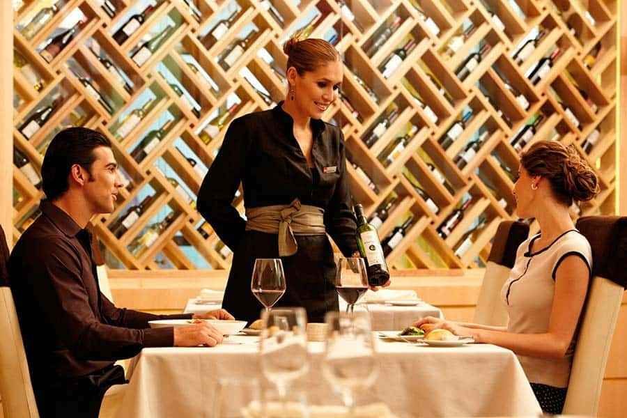 Una mujer está sirviendo a un hombre y a una mujer en una mesa en un restaurante.