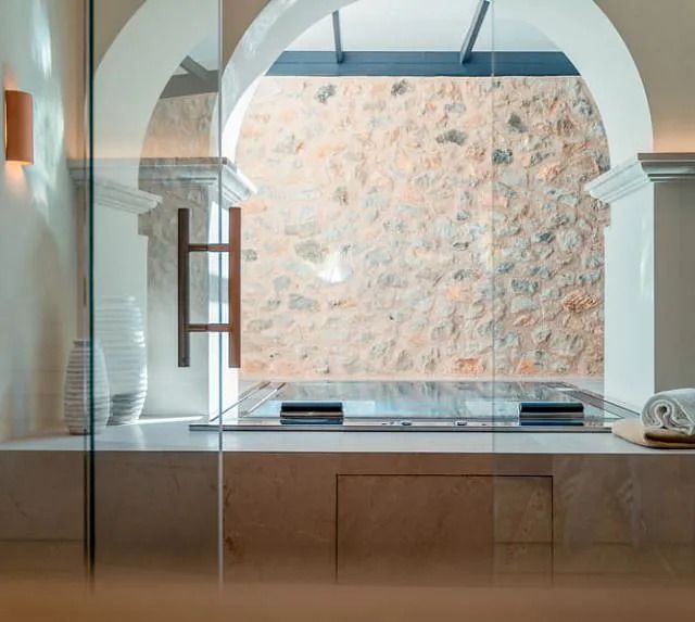 Un baño con una puerta de cristal y una pared de piedra detrás.