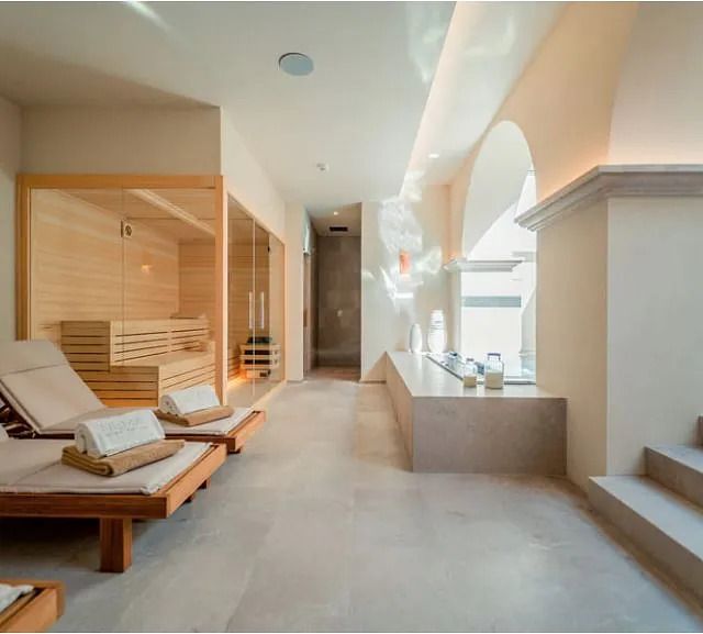 Un largo pasillo con sillas y una sauna al fondo.