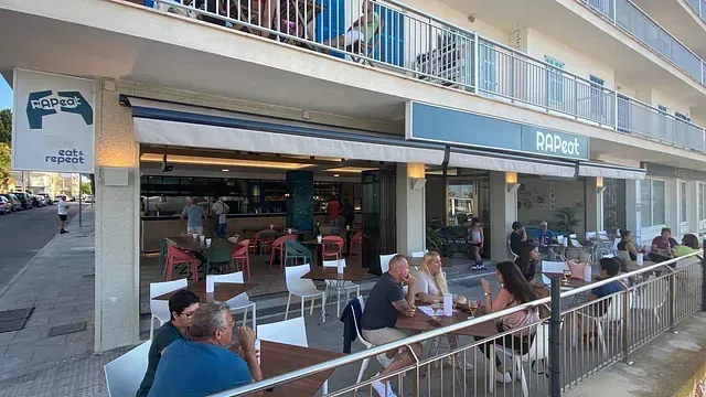 Un grupo de personas están sentadas en mesas afuera de un restaurante.