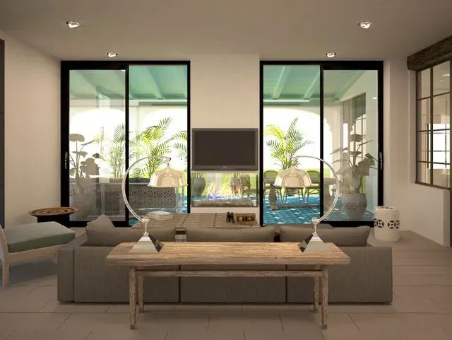 Una sala de estar con sofá, mesa, televisión y puertas corredizas de vidrio.