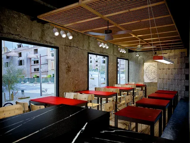 Un restaurante con mesas y sillas rojas y un ventilador de techo.