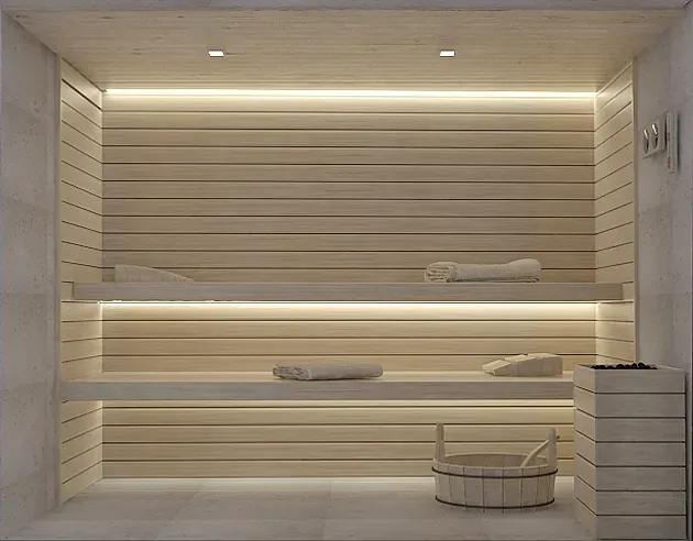 Una sauna de madera con un cubo y toallas en los estantes.