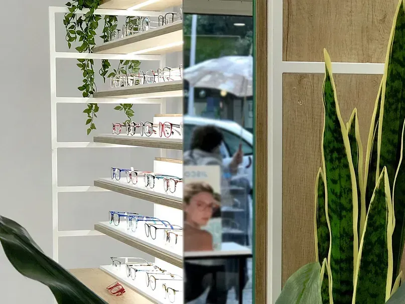 Una mujer está sentada en una mesa en una tienda de óptica.