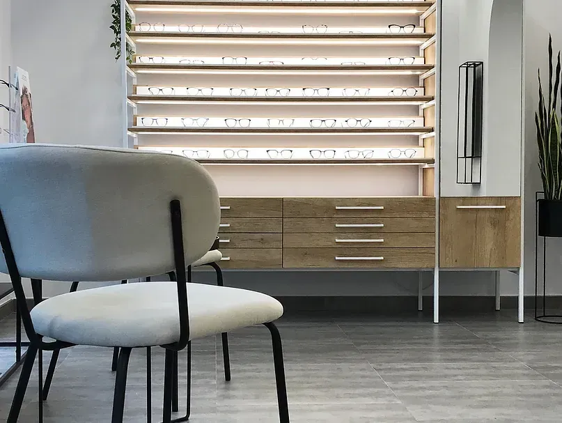 Una silla está delante de un estante con vasos encima.