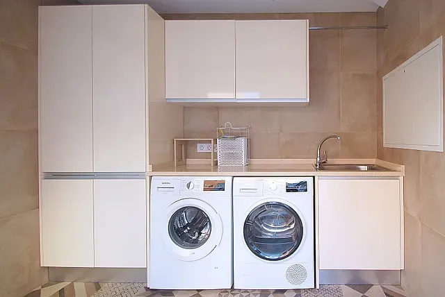 Un lavadero con lavadora, secadora y fregadero.