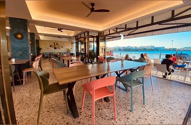 Un restaurante con mesas y sillas y vista al mar.