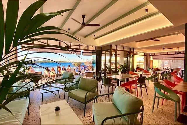 Un restaurante con mesas y sillas y vista al mar.