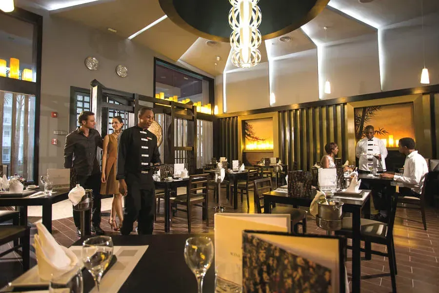 Un restaurante con gente sentada en mesas y una lámpara colgando del techo.